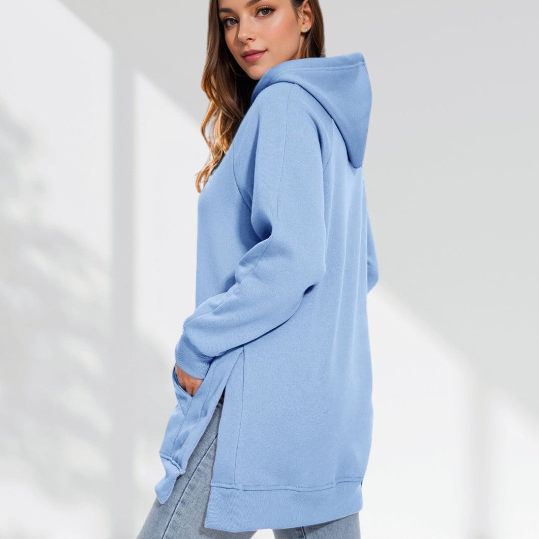 Woman wearing a baby blue hoodie dress, standing sideways and facing forward to show the fit and style.