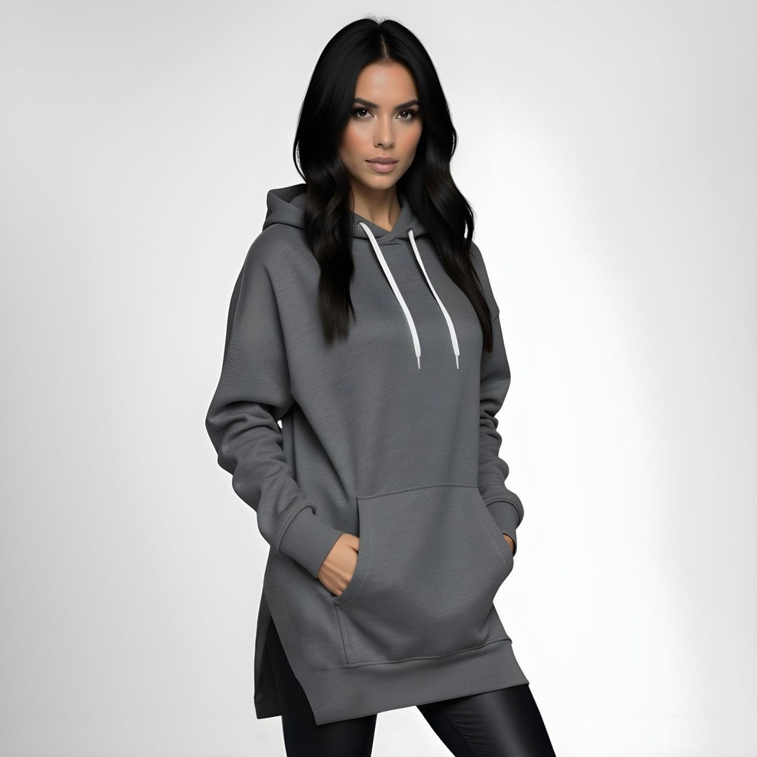 Woman wearing a dark gray hoodie dress, standing and facing forward to show the fit and style.