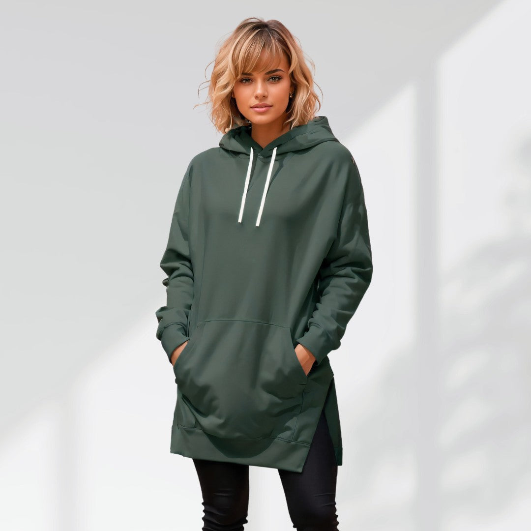 Woman wearing a green hoodie dress, standing and facing forward to show the fit and style.